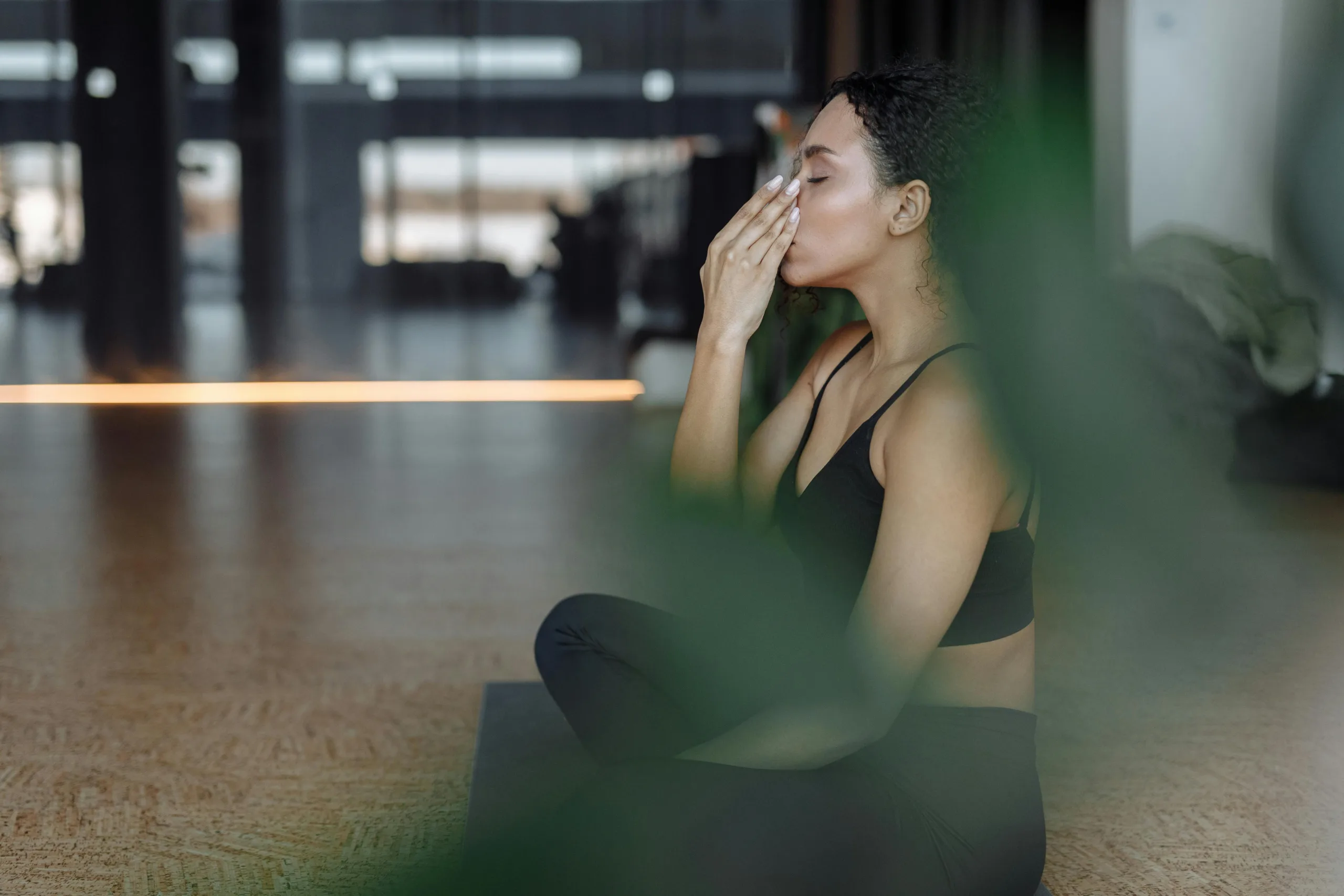 a woman sitting on a yoga mat doing breathing 